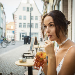 Portrait of woman drinking glass in city