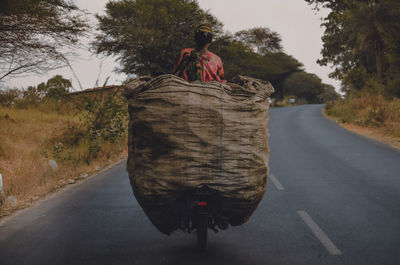 Portrait of man riding motorcycle on road against sky