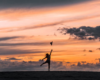 Low angle view of silhouette man jumping against sky during sunset