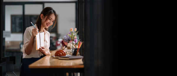 Young woman looking away while sitting on table