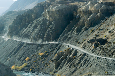 Aerial view of land and mountains. driving at the edge of desert himalayas. dust trails of vehicle.