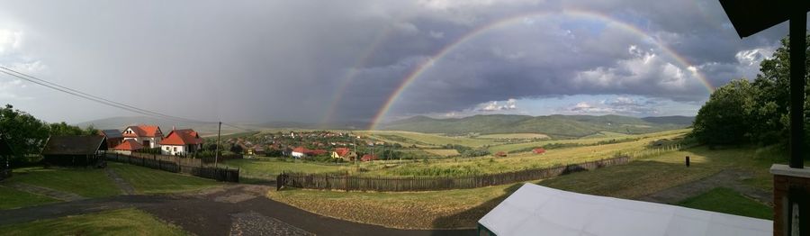 Panoramic view of agricultural landscape against rainbow in sky