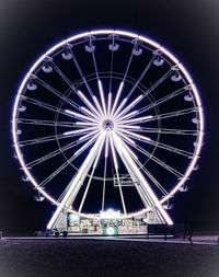 Illuminated ferris wheel against sky at night