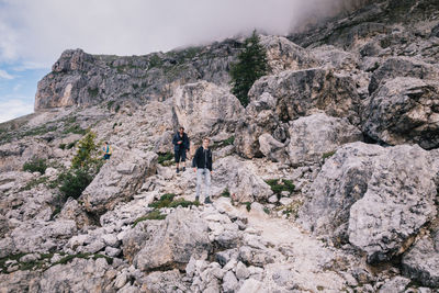 Full length of men walking on rocky land against sky