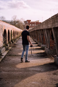 Rear view of man walking on bridge against sky