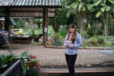 Portrait of smiling young woman standing at park