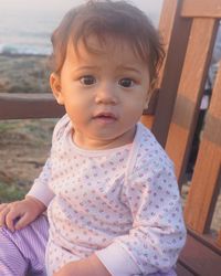 Portrait of cute girl sitting on chair at beach