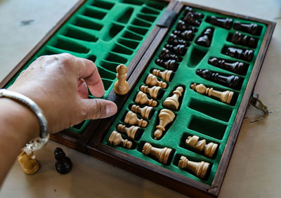 Cropped hand of man touching chess board