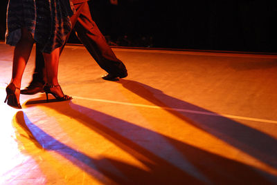 Low section of man standing on floor at night