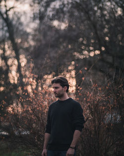 Young man looking away in forest