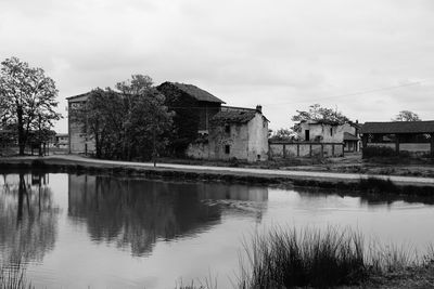 Buildings by lake against sky