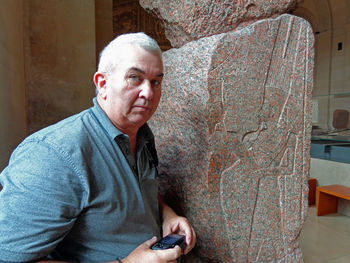 Portrait of senior man holding camera at museum