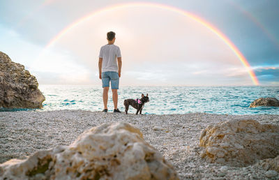 Man and french bulldog dog on the beach