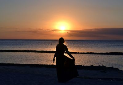 Silhouette man on beach against sky during sunset