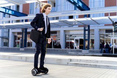 Italy, florence, young businessman riding hoverboard in the city