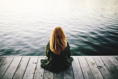 Rear view of woman looking at pier over lake