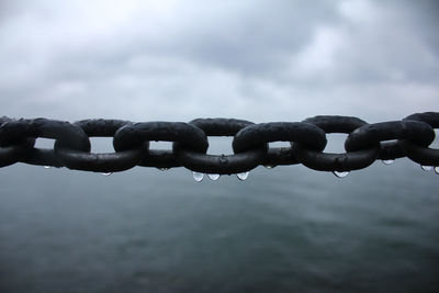 Close-up of metal chain against sky