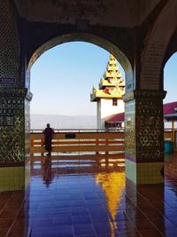Rear view of men standing on tiled floor against sky