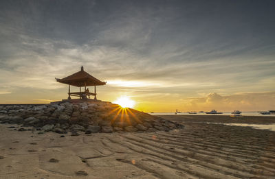 Lifeguard hut on beach against sky during sunset