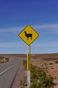 Road sign against blue sky