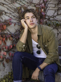 Thoughtful man in casual clothing with sunglasses hanging on t-shirt sitting on stair