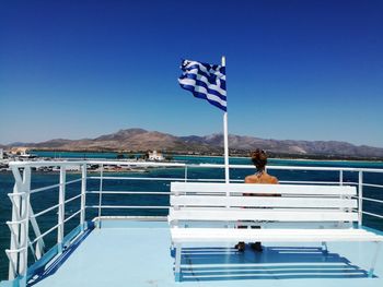 Flag on sea against clear blue sky