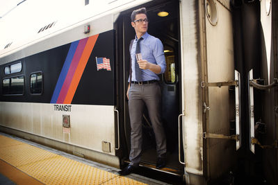 Businessman holding ticket while disembarking from train