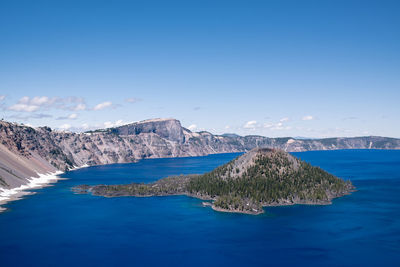 Scenic view of sea and mountains against blue sky