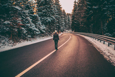 Rear view of woman walking on road