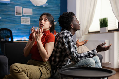 Young couple looking away while sitting on sofa