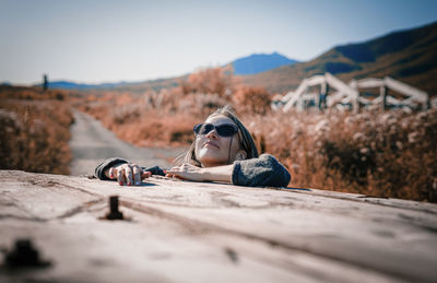 Woman lying down on wood against sky