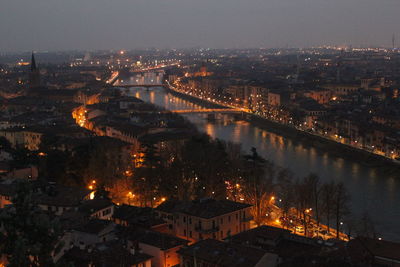 High angle view of illuminated bridge over river by buildings in city