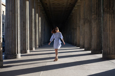 Smiling young woman walking amidst columns