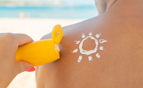 Midsection of woman holding yellow umbrella on beach