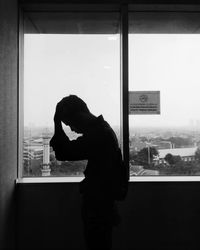 Side view of silhouette woman standing against window