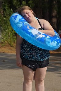 Young woman relaxing on inflatable ring while standing at footpath