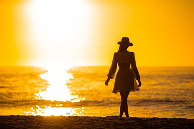 Silhouette woman walking on beach during sunset