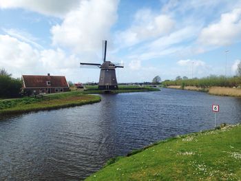 Traditional windmill on field against cloudy sky