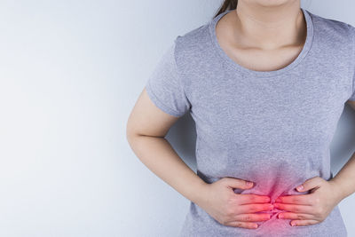 Midsection of woman standing against wall