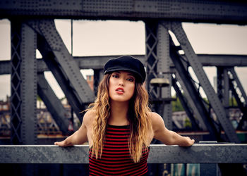Portrait of beautiful young woman wearing flat cap against built structure