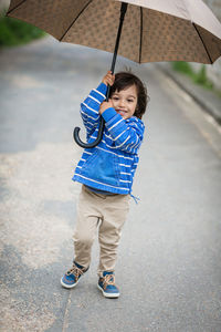 Little handsome baby boy playing with umbrella outdoor