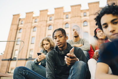 Low angle view of male friends sitting in city