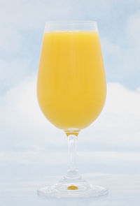 Close-up of yellow drink on table against sky