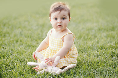 Cute boy sitting on grass in field