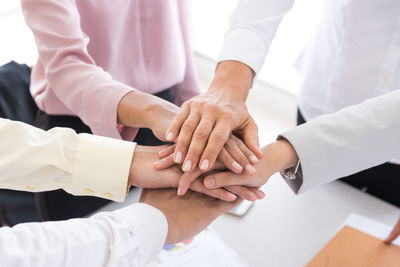 Midsection of business colleagues stacking hands