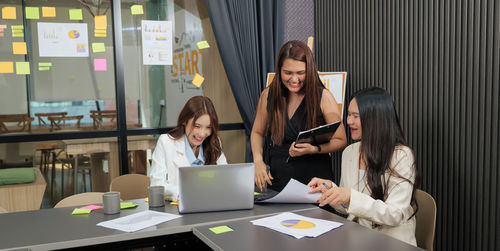 Smiling friends using laptop at office