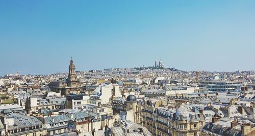 Aerial view of buildings in town against clear blue sky