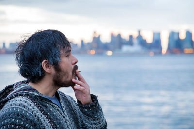 Portrait of young man looking away against sea