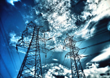 Low angle view of electricity pylon against cloudy sky