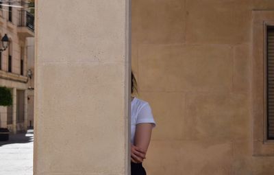 Woman hiding behind pillar